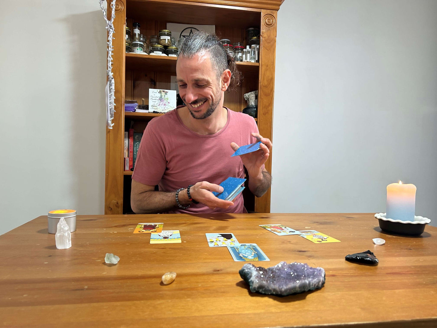 Man playing a card game at a table with crystals and candles