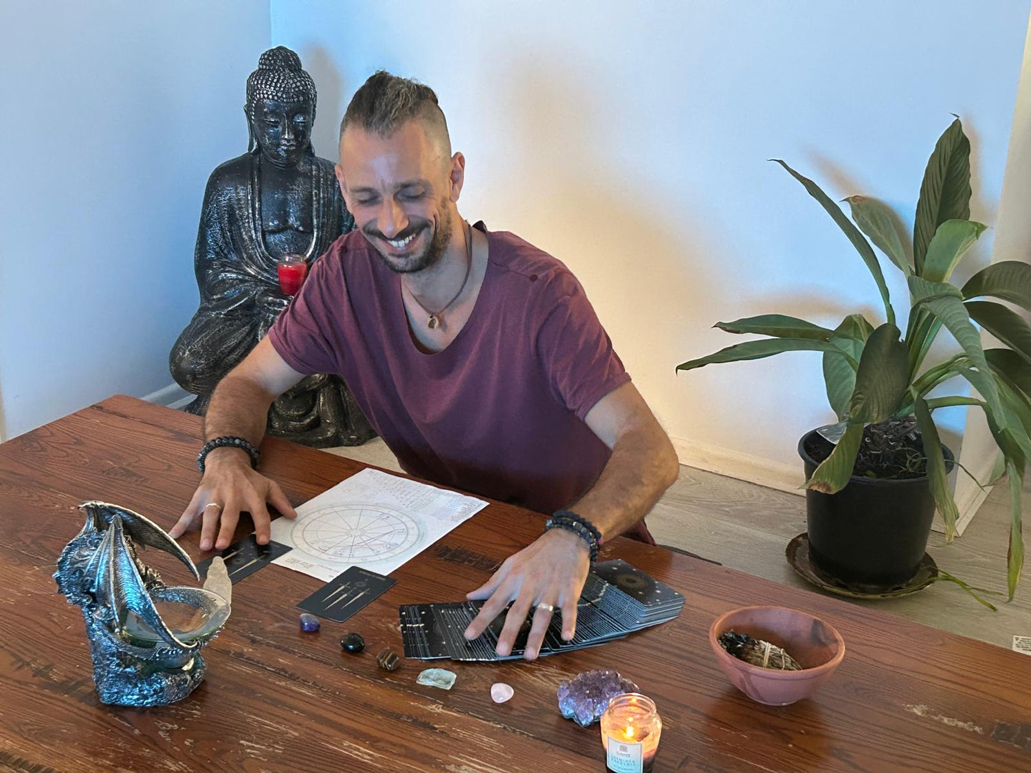 Man performing a Birth Chart & Tarot Reading session with crystals and candles on a table.